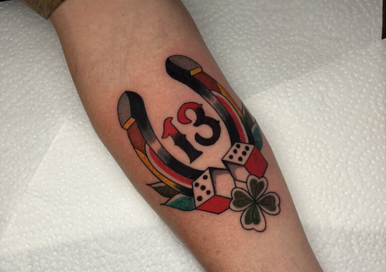 Traditional hoefijzer tattoo met het nummer 13, dobbelstenen en klavertje vier op de onderarm door StayXGold Tattoo Barendrecht