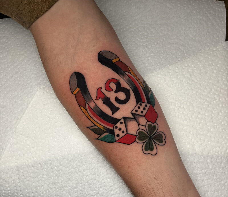 Traditional hoefijzer tattoo met het nummer 13, dobbelstenen en klavertje vier op de onderarm door StayXGold Tattoo Barendrecht