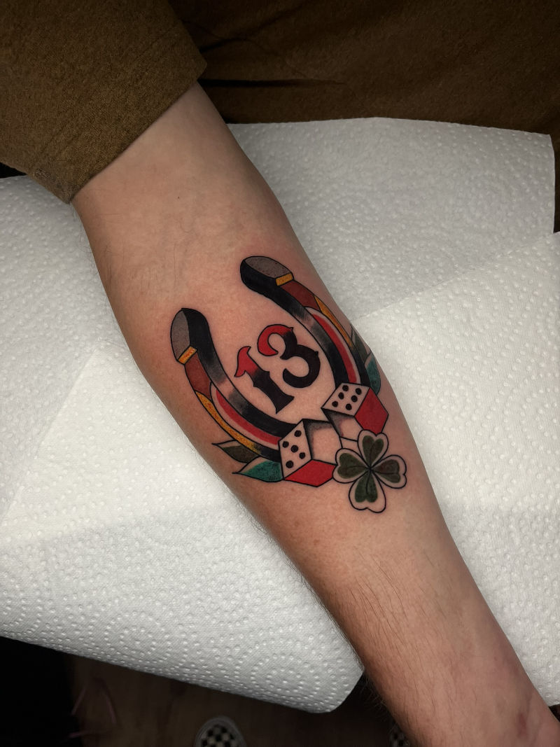 Traditional hoefijzer tattoo met het nummer 13, dobbelstenen en klavertje vier op de onderarm door StayXGold Tattoo Barendrecht